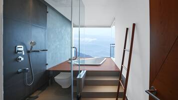 A modern bathroom with a glass shower enclosure, a wooden vanity, and a view of the mountains.