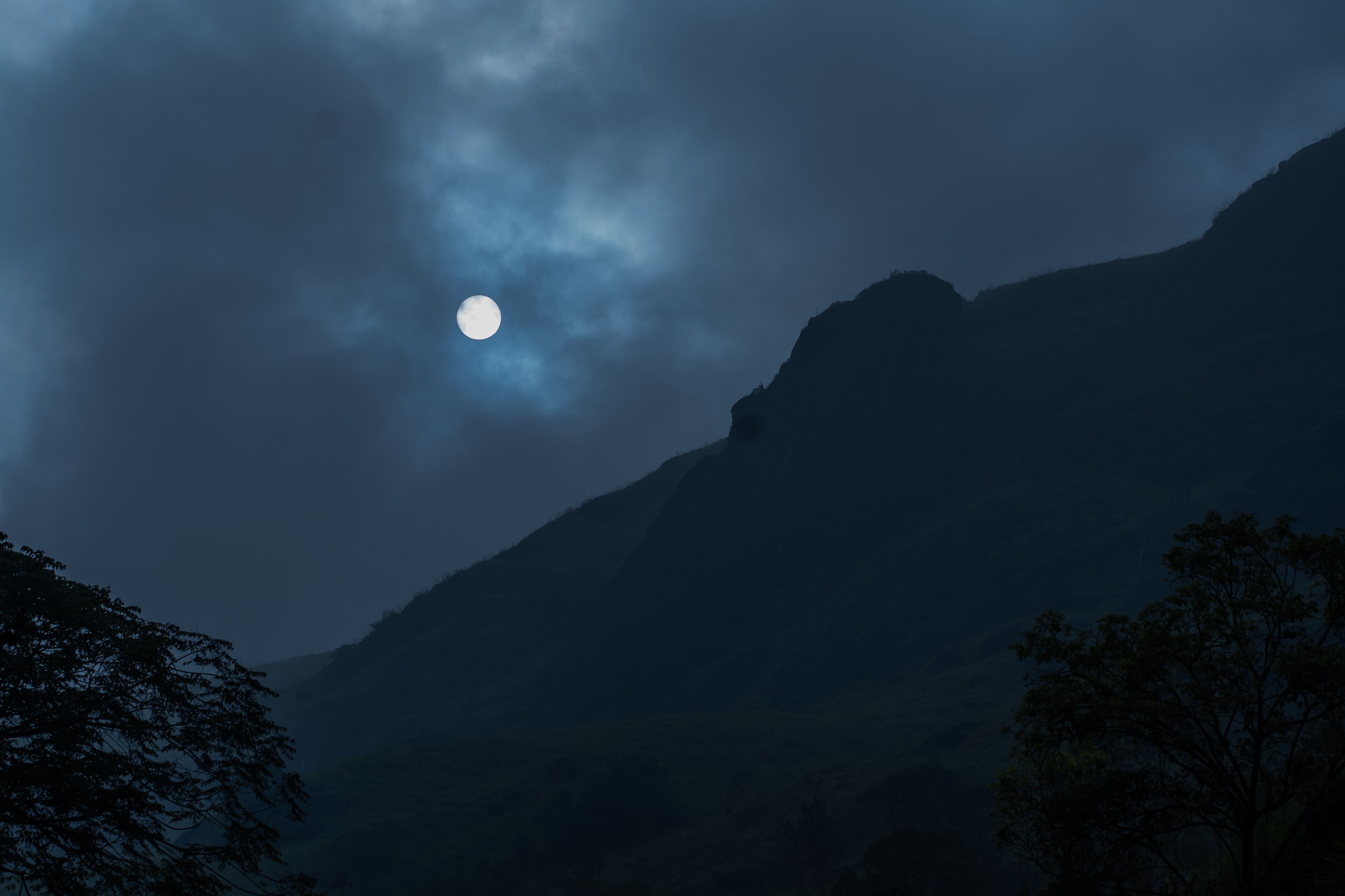 Un paysage de montagne avec une lune visible.