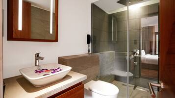 Un bagno moderno con box doccia in vetro, lavandino bianco con decorazioni floreali e mobile vanitario in legno.