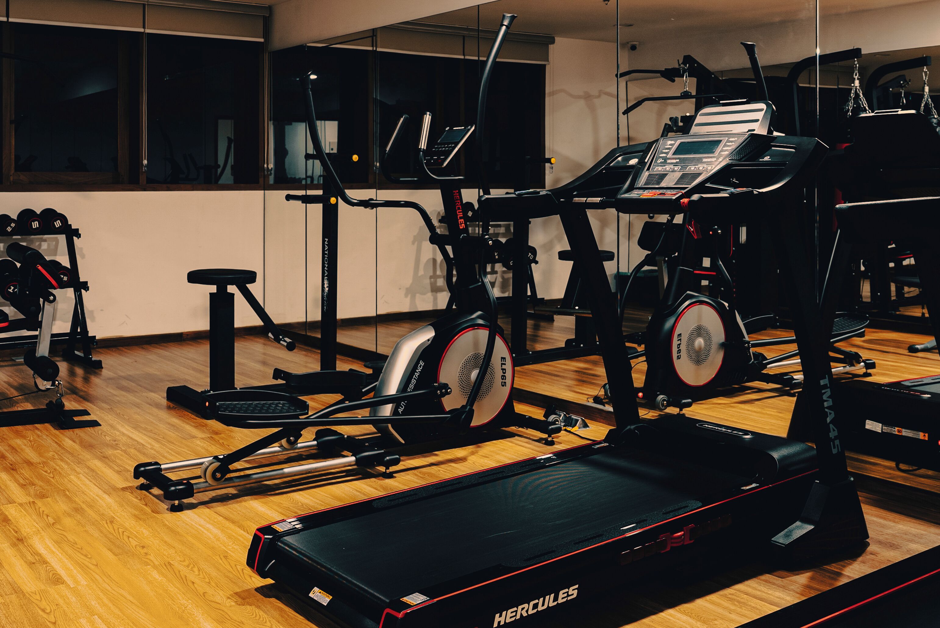 A gym with various exercise equipment including treadmills, ellipticals, and weight machines.
