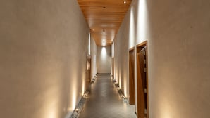 A long, narrow hallway with wooden ceiling panels and walls, leading to doors at the end. - The Valle by Kondody Hotels (Devikolam)