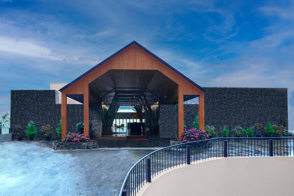 A modern building with a stone facade and a wooden entrance canopy. - The Valle by Kondody Hotels (Devikolam)