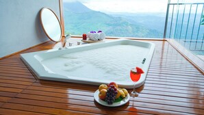 A spa area with a hot tub, wooden flooring, a mirror, towels, and a fruit plate. - The Valle by Kondody Hotels (Devikolam)