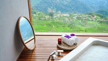 Enjoy a panoramic view of the lush valley from the bathtub, surrounded by a serene atmosphere.