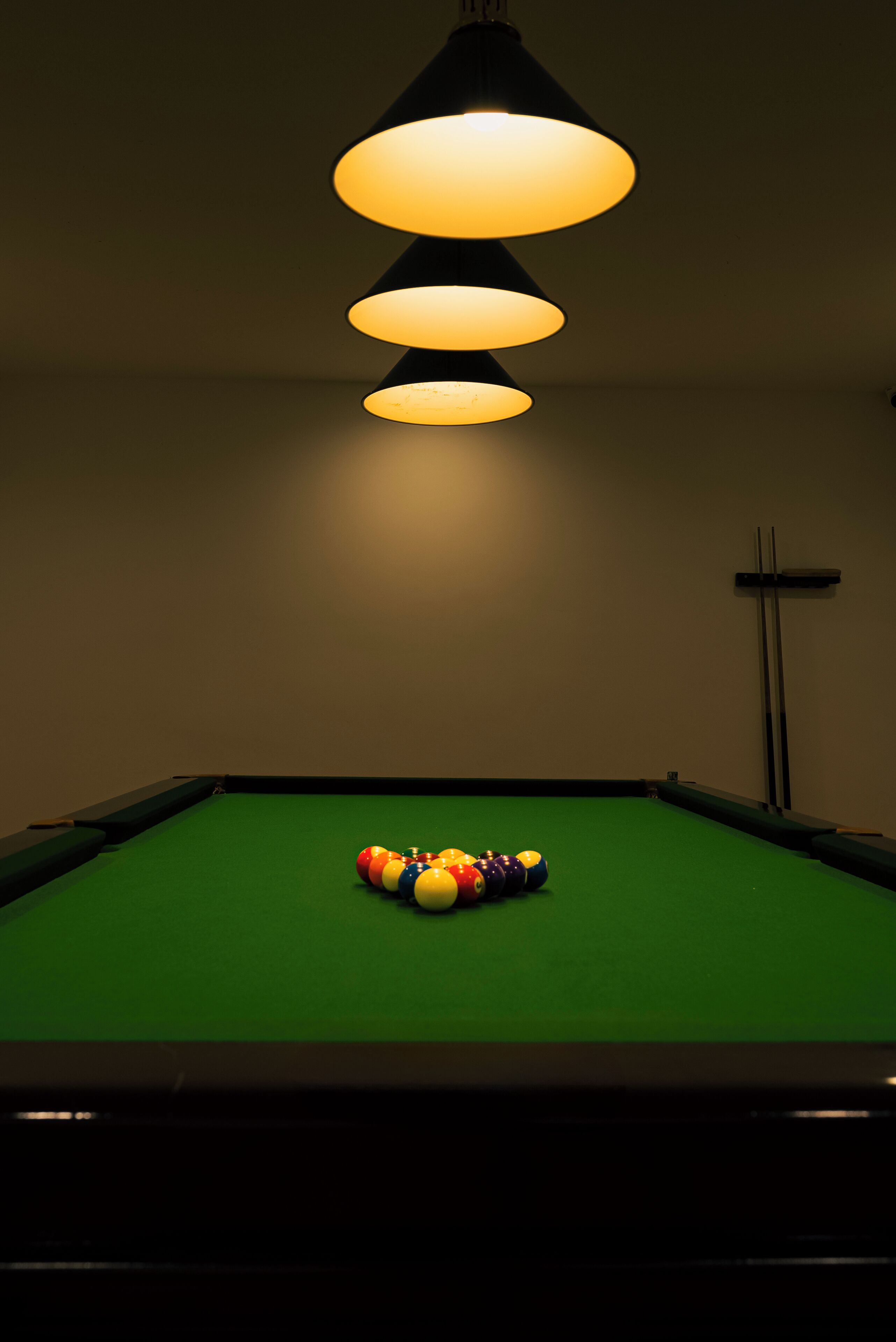 A pool table with a green felt surface and a colorful arrangement of billiard balls in the center.