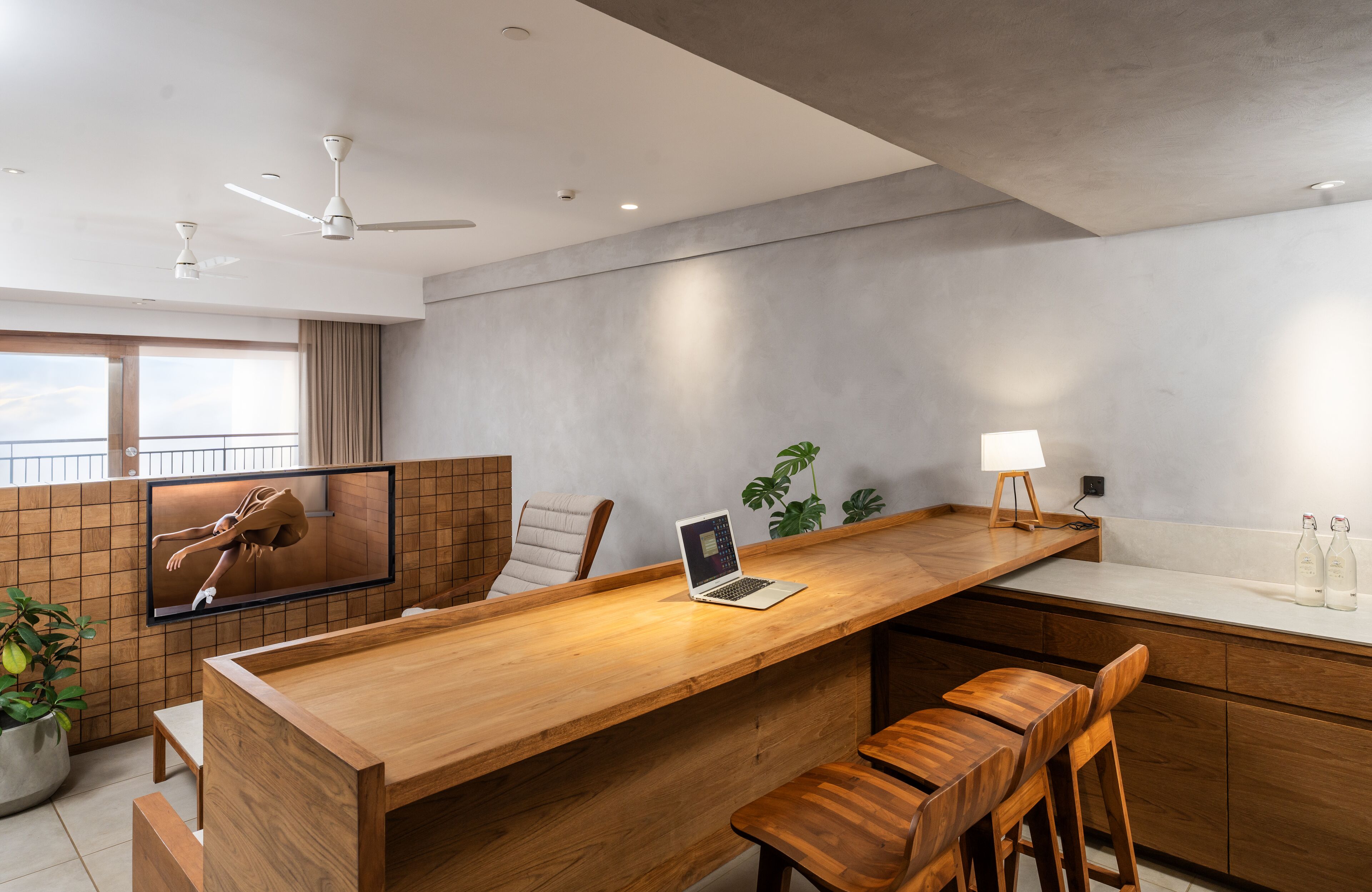Una cocina moderna con una isla de madera, una computadora portátil y taburetes de bar.