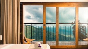 Habitación de hotel con una ventana grande, una cama y vistas a un paisaje montañoso.