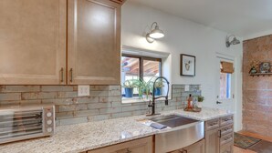 Eine Küche mit Holzschränken, einer Edelstahl-Spüle, Granit-Arbeitsplatten und einem eingebauten Toaster.