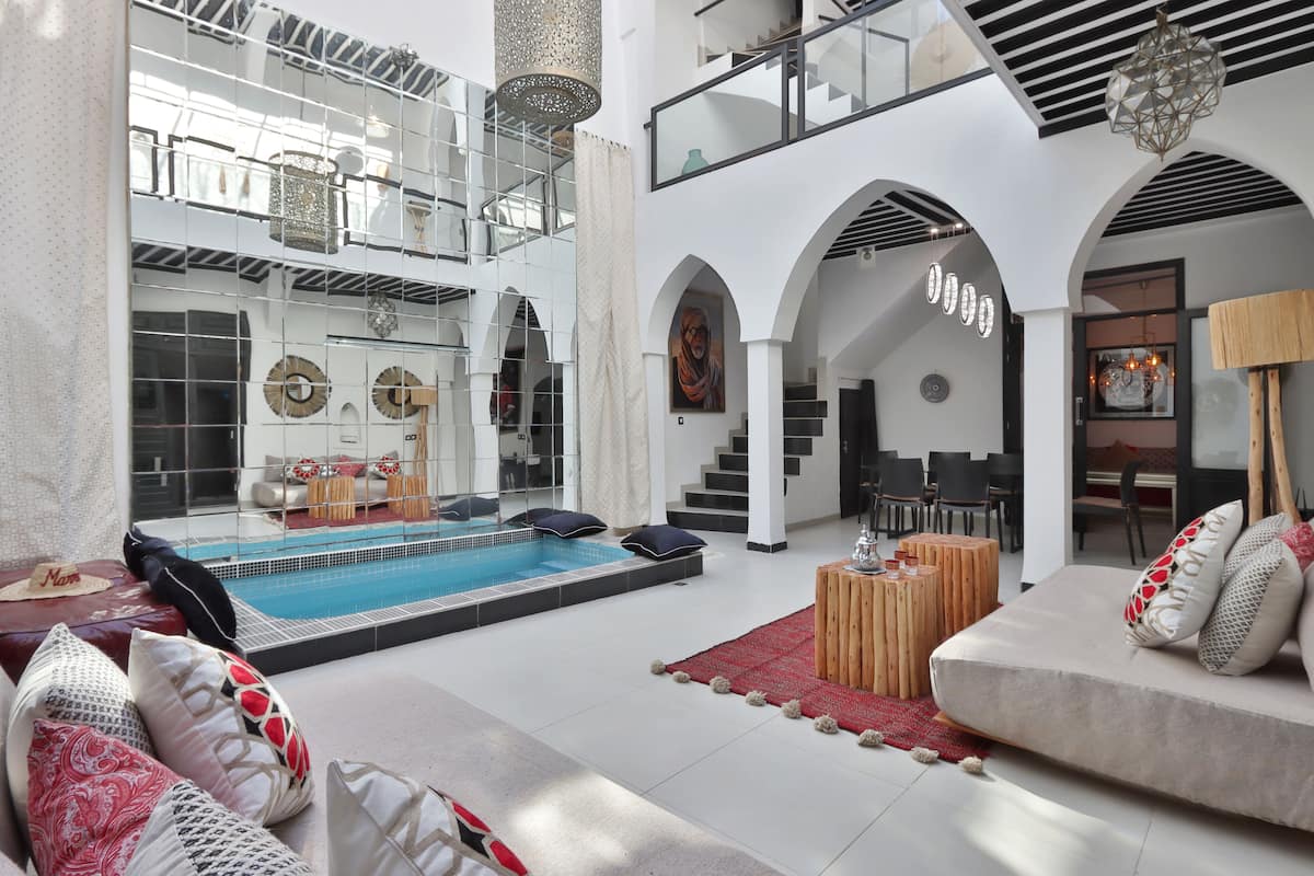 Un vaste espace intérieur doté d’une piscine, de coins salon et d’un escalier menant à un niveau supérieur.