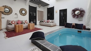 A modern interior with a pool, sofas, and decorative mirrors. - Riad Modern bed & breakfast  (Marrakech)