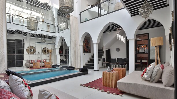 A spacious living area with a pool, a sofa set, and a wooden coffee table. - Riad Modern bed & breakfast  (Marrakech)