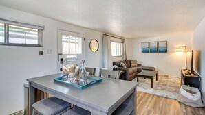 Uma sala de estar moderna com área de jantar, sofá, mesa de centro e luminária.