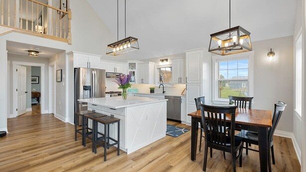 A spacious kitchen with a central island, wooden flooring, and pendant lighting. - Heron House, Beautiful seaside retreat close to Cavendish (North Rustico)