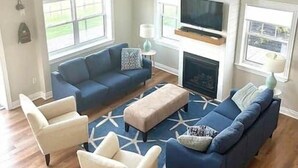A modern living room with a blue sofa set, a beige armchair, and a patterned rug. - Heron House, Beautiful seaside retreat close to Cavendish (North Rustico)