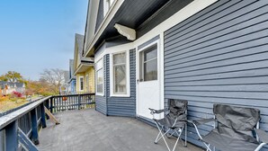 A covered porch with two folding chairs, a wooden deck, and a view of neighboring houses. - Charming Buffalo Apartment: 2 Mi to Downtown (Buffalo)
