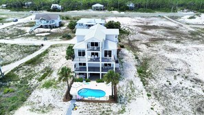 A multi-story beachfront property with a swimming pool, multiple balconies, and a beach access path.