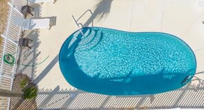 An aerial view of a swimming pool with a surrounding deck and lounge chairs.