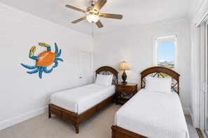 A bedroom with two beds, a ceiling fan, a nightstand with a lamp, and a decorative crab wall art piece. - Private Pool Beach Front Sleeps 18 Family home (St, George Island)