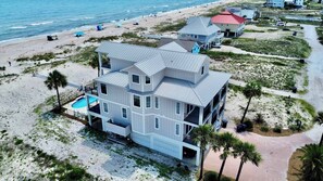 A multi-story beachfront house with a swimming pool, beach access, and a view of the ocean.