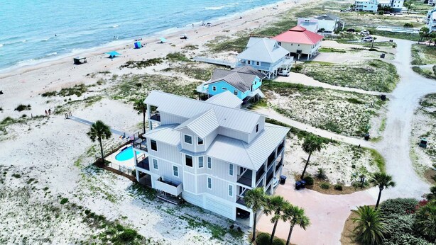 A coastal property with a large house, a swimming pool, and a beach view.