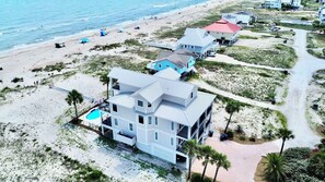 A coastal property with a large house, a swimming pool, and a beach view.