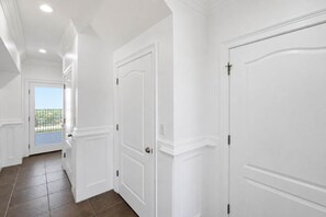 A hallway with white doors, a view to the outside, and a balcony. - Private Pool Beach Front Sleeps 18 Family home (St, George Island)