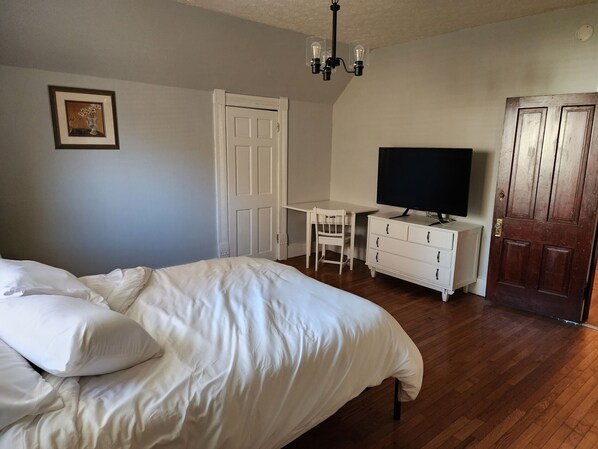 A bedroom with a bed, a desk, a television, and a wardrobe.