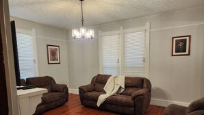 Ein Wohnzimmer mit zwei braunen Sofas, einem weißen Konsolentisch und einer Kronleuchter.