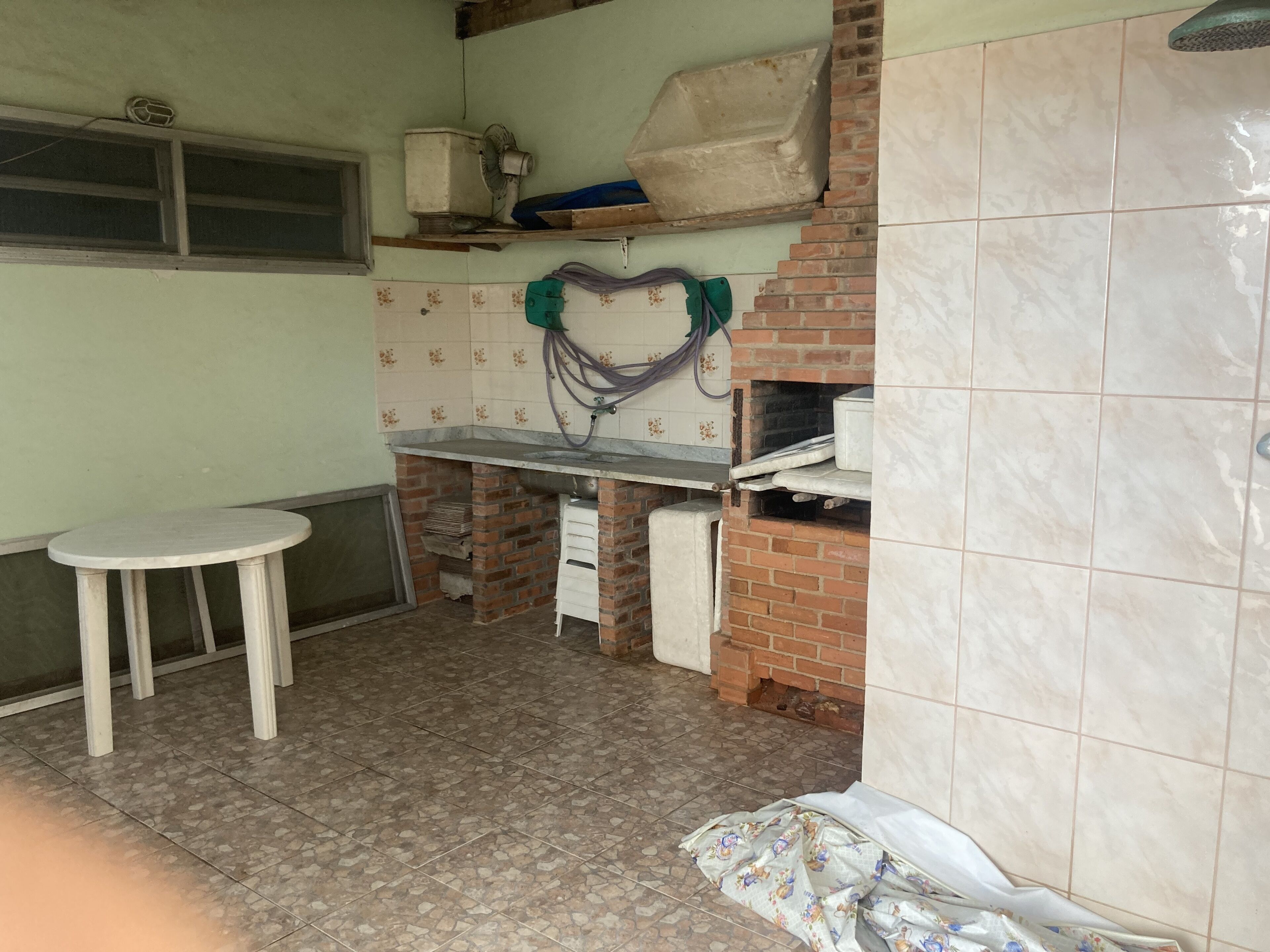 A kitchen with a tiled floor, a small round table, a brick oven, and a window.