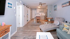 A compact living space with a kitchenette, a dining area, and a seating area with a sofa and armchair.