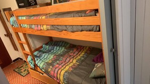 Ein Stockbett mit bunter Bettwäsche und einem Holzrahmen.