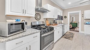 A modern kitchen with white cabinets, a stainless steel range, and a microwave.