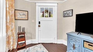 A room with a white door, a framed map, a television on a blue dresser, and a patterned curtain.