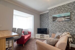 Relax in this stylish living room with a dining table, sofa, armchair, and entertainment unit.