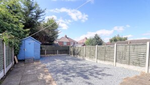 A backyard with a gravel area, a blue shed, and a wooden fence. - Highfield House cosy 4 bedroom (Scunthorpe)