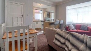 A compact living space with a dining area, a sofa, and a kitchen in the background. - Highfield House cosy 4 bedroom (Scunthorpe)
