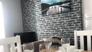 A dining area with a brick wall, a painting, and a sofa. - Highfield House cosy 4 bedroom (Scunthorpe)