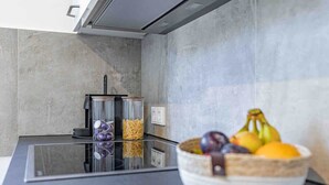 A modern kitchen with a glass-top island, a bowl of fruit, and a coffee maker. - SMS-Homes I Timeout at the Alpsee-Lake (Immenstadt im Allgäu)