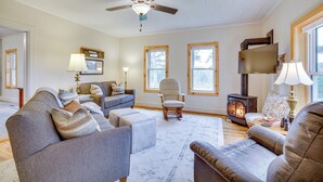 Una sala de estar con chimenea, sofás, un sillón y televisor.