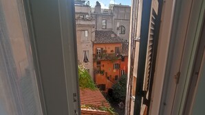 A narrow corridor with a view of adjacent buildings, including a red-roofed structure with potted plants. - Apartment in the historic center of Rome (Roma)