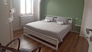 A bedroom with a bed, a chair, a window, and a green wall. - Apartment in the historic center of Rome (Roma)