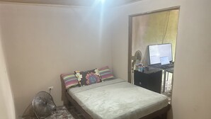 A bedroom with a bed, a fan, and a desk with a laptop. - Arenal Family House (La Fortuna)