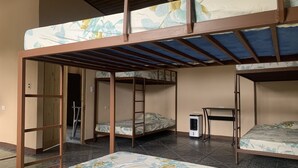 A dormitory room with bunk beds, a ladder, a desk, and a heater. - Arenal Family House (La Fortuna)