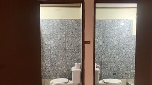 A bathroom with two toilets, marble tiles, and patterned floor tiles. - Arenal Family House (La Fortuna)