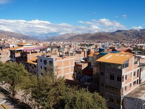 Un paisaje urbano con una combinación de edificios residenciales y comerciales, una destacada torre de agua azul y montañas al fondo.