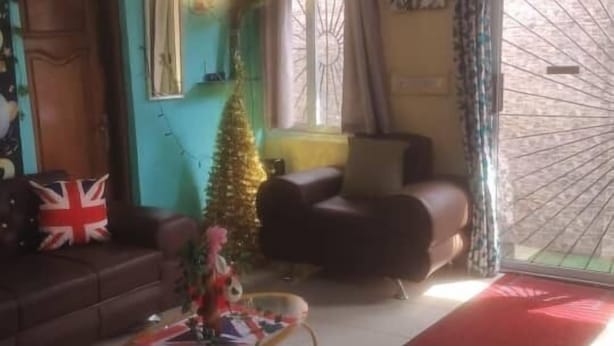 Een woonkamer met een bank, een kerstboom en een salontafel.