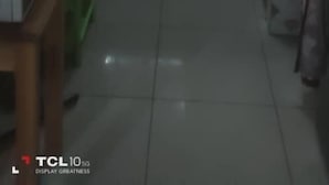 Een keuken met een raam, kastjes en een groene plastic prullenbak.