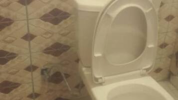 A toilet with a closed seat in a bathroom with patterned tiles.