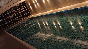 A swimming pool with a tiled floor and a glass barrier.