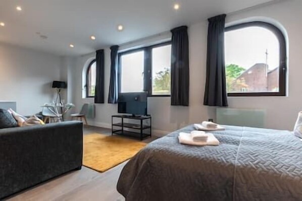 Relax in a serene space with a large bed, flat-screen TV, and a comfortable armchair.